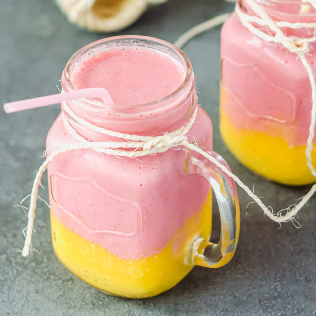 Zwei Gläser mit Erdbeer-Mango-Smoothie in Schichten