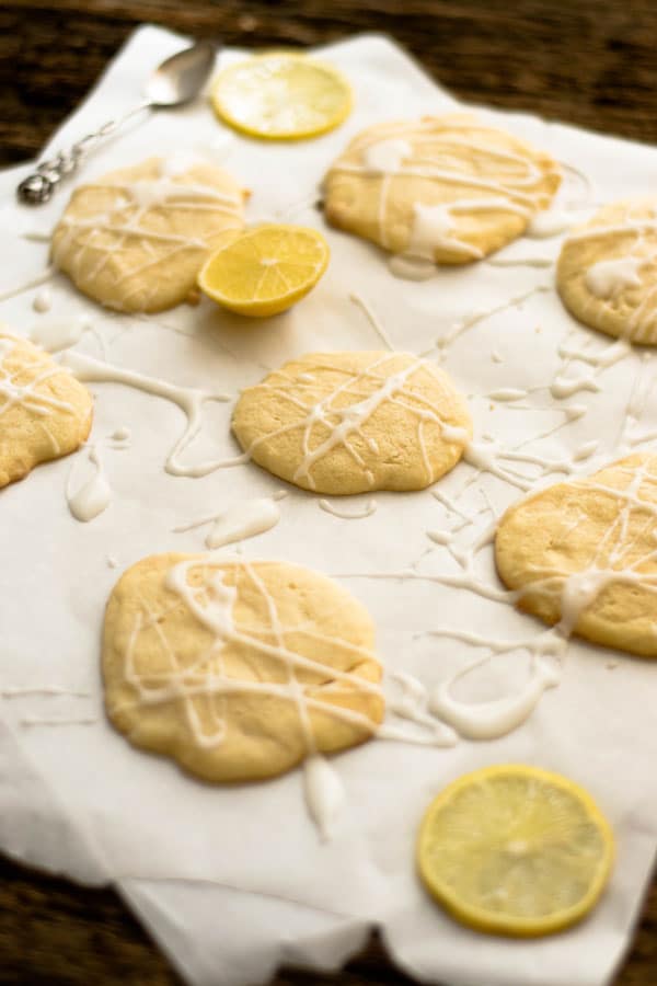 white chocolate lemon cookies auf weißem Backpapier mit Zuckerguss und Zitronenscheiben
