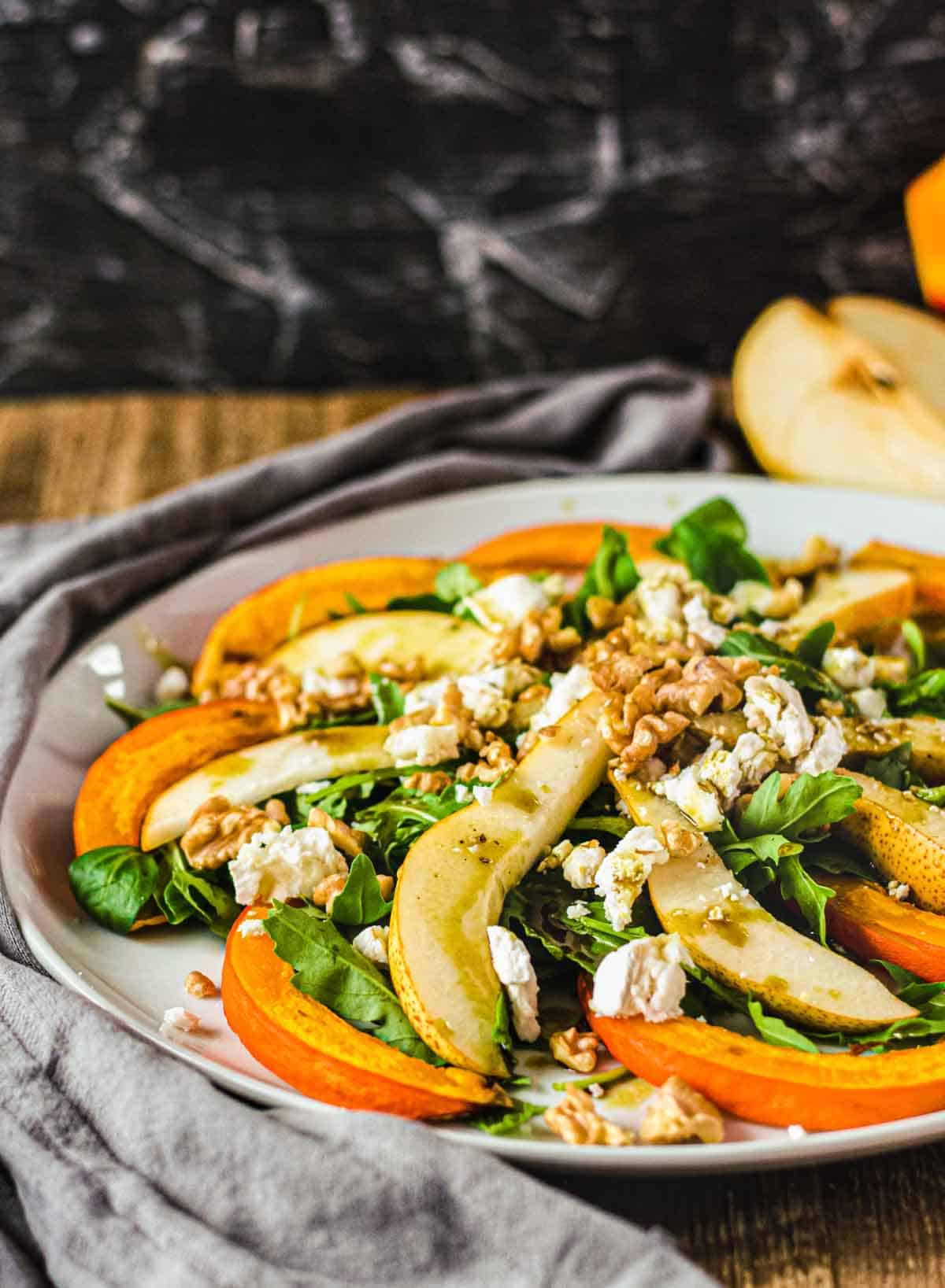 Herbstsalat auf einem weißen runden Teller auf Holztisch