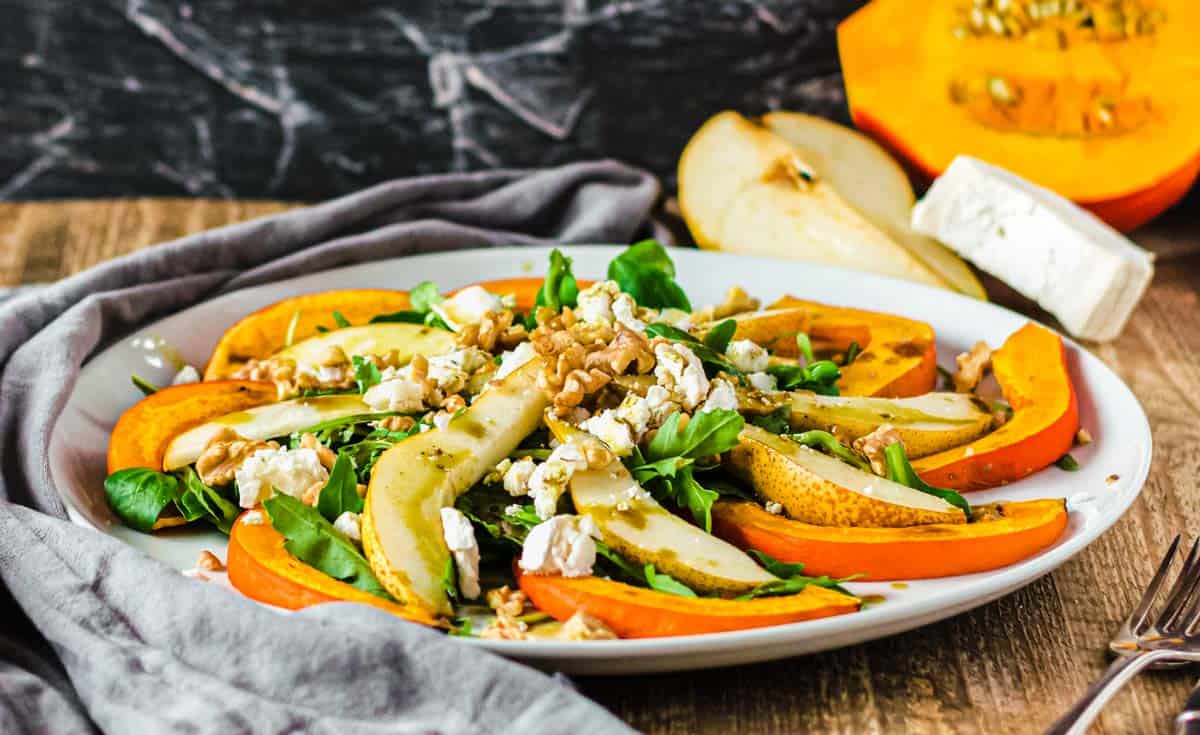 Herbstsalat auf einem weißen Teller auf Holztisch