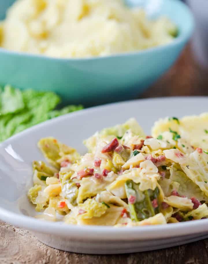 Wirsing mit Schinkenwürfeln und Kartoffelpüree auf einem weißen Teller