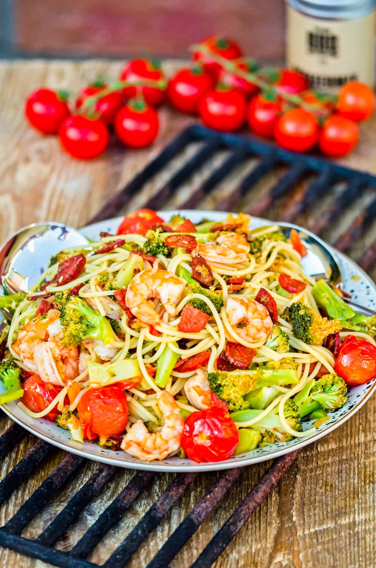 Spaghetti mit Garnelen und Gemüse mit Tomaten im Hintergrund