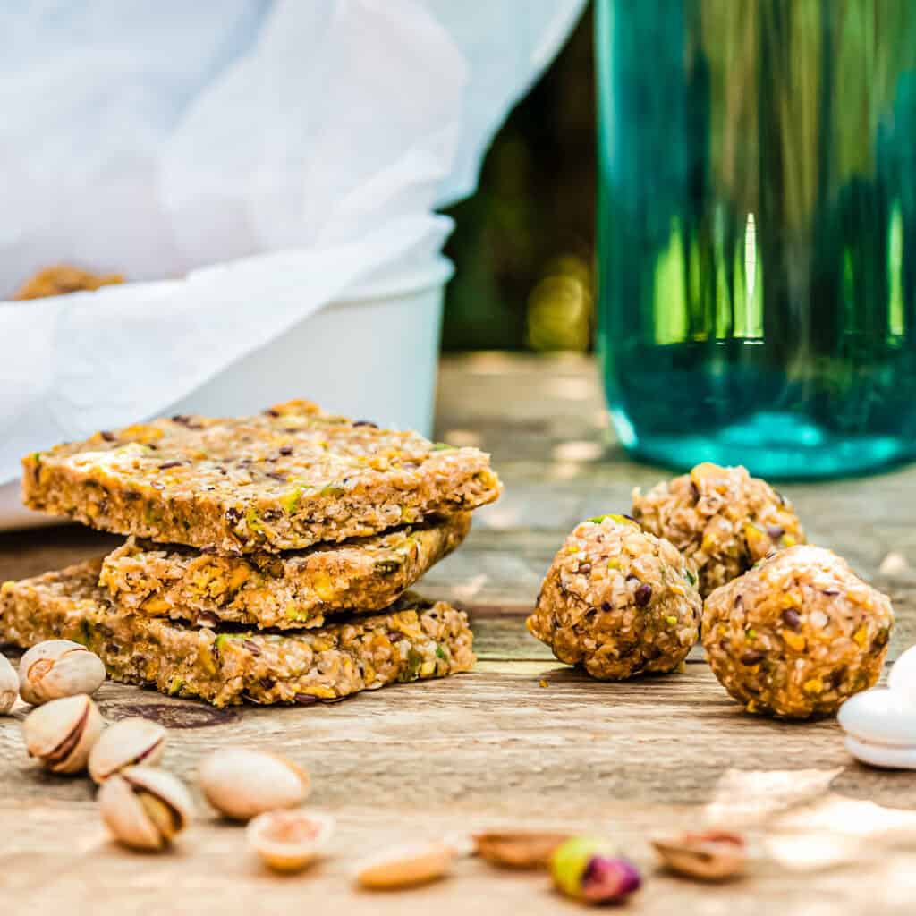 Energy Balls und Energieriegel nebeneinander auf Holztisch