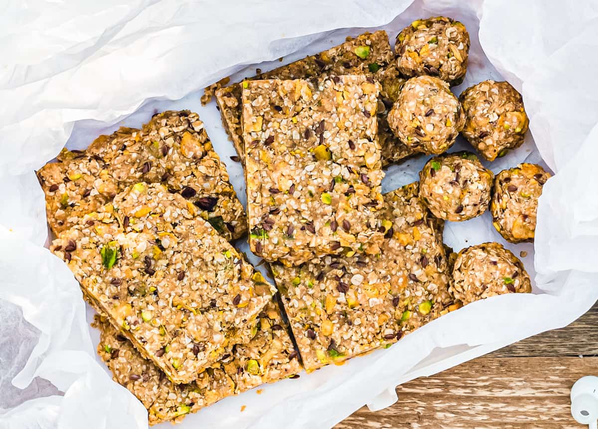 Energy Balls und Energieriegel nebeneinander in Dose auf weißem Papier