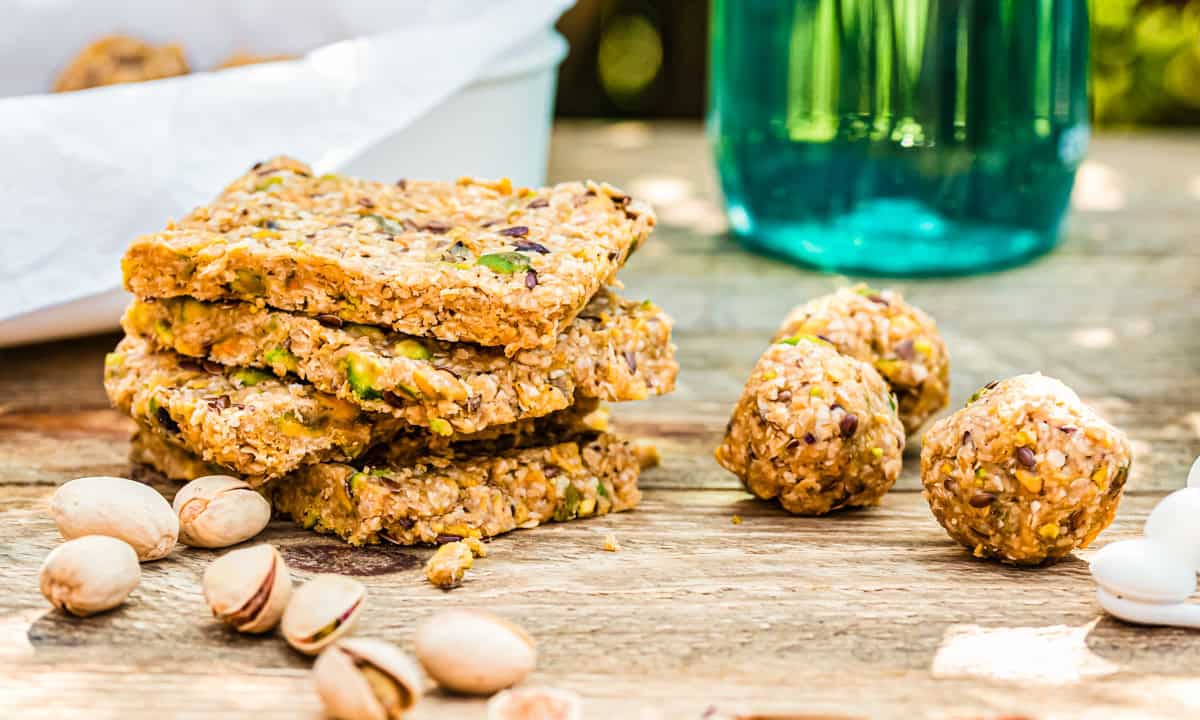 Energy Balls und Energieriegel nebeneinander auf Holztisch