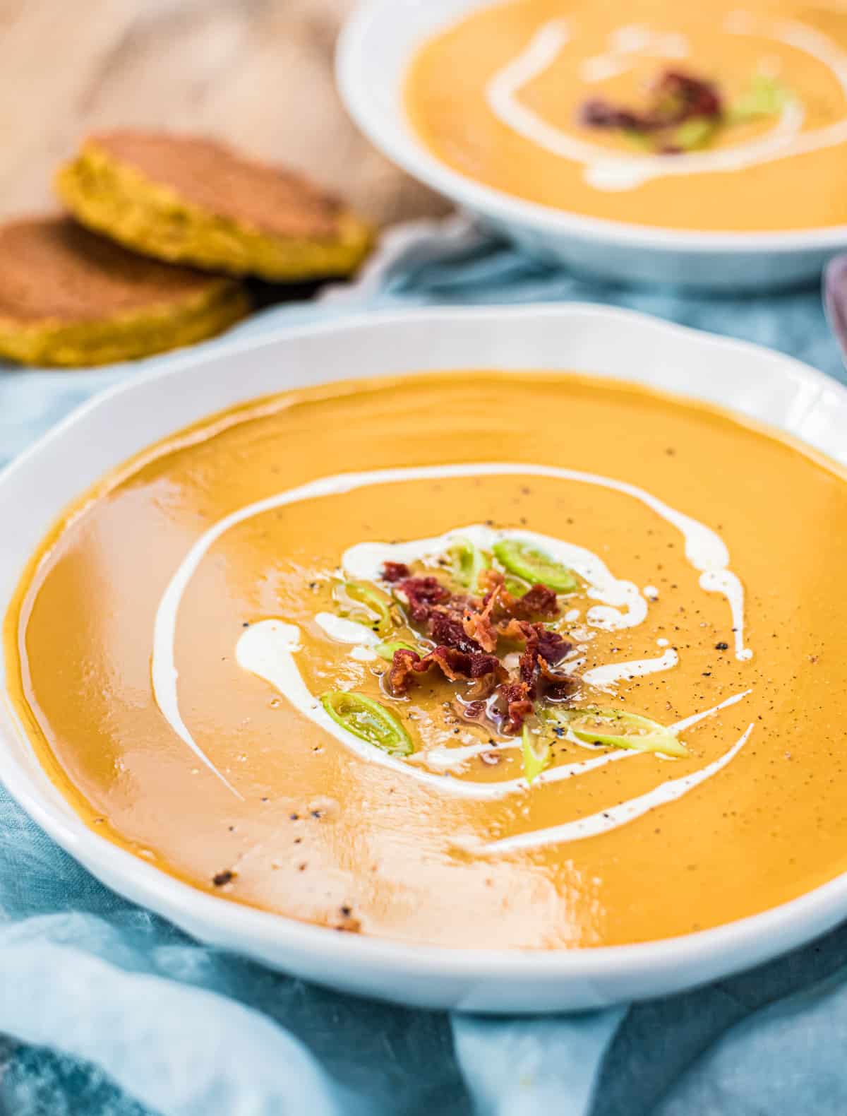 Süßkartoffelsuppe in einer weißen Schüssel. Nachaufnahme. Brot im Hintergrund.