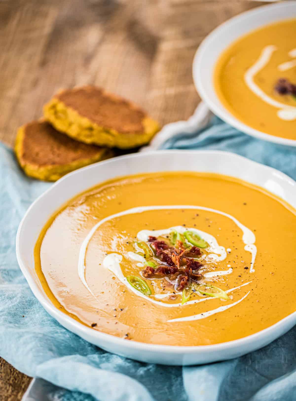 Süßkartoffelsuppe in einer weißen Schüssel. Nachaufnahme. Brot im Hintergrund.