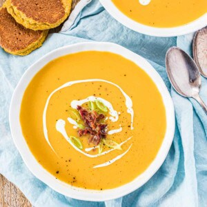 zwei weiße Schüsseln mit Süßkartoffelsuppe, mit Bacon und Frühlingszwiebeln. Von oben fotografiert.