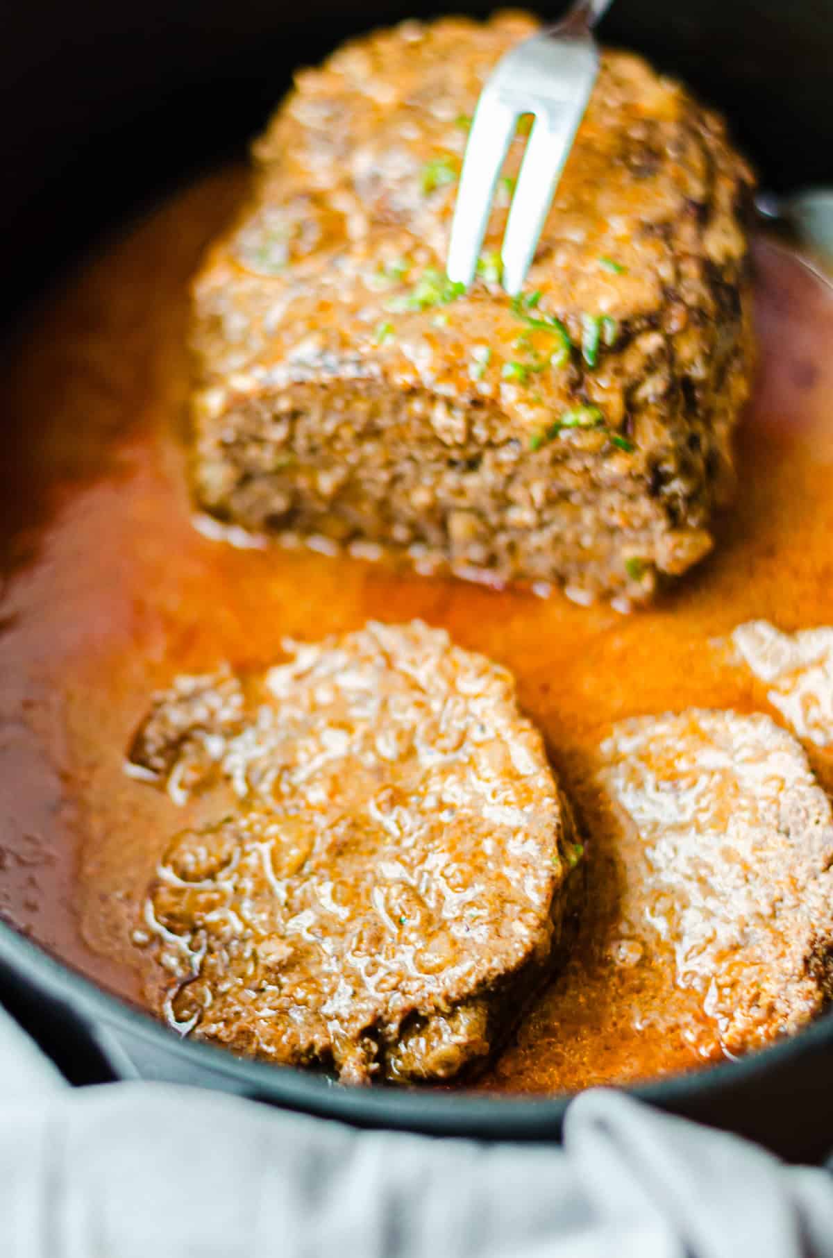 angeschnittener Hackbraten mit Gabel in einem Bratentopf, Nahaufnahme
