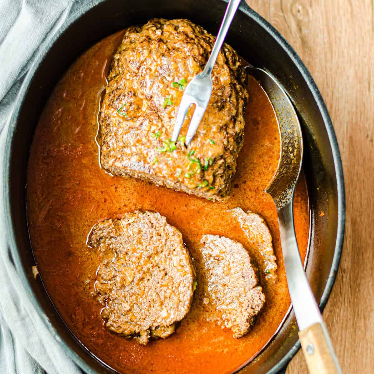 angeschnittener Hackbraten mit Gabel in einem Bratentopf, von oben