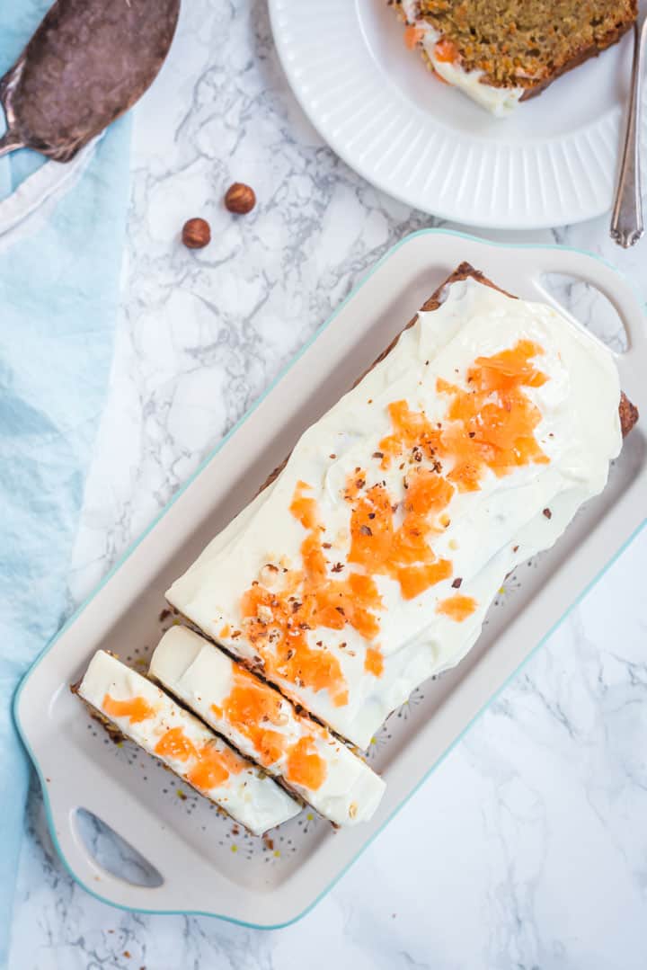 Karottenkuchen mit Guss von oben auf einer hellen Kuchenplatte fotografiert