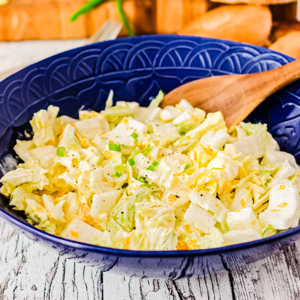 Chinakohlsalat in einer dunkelblauen Schüssel mit Holzlöffel