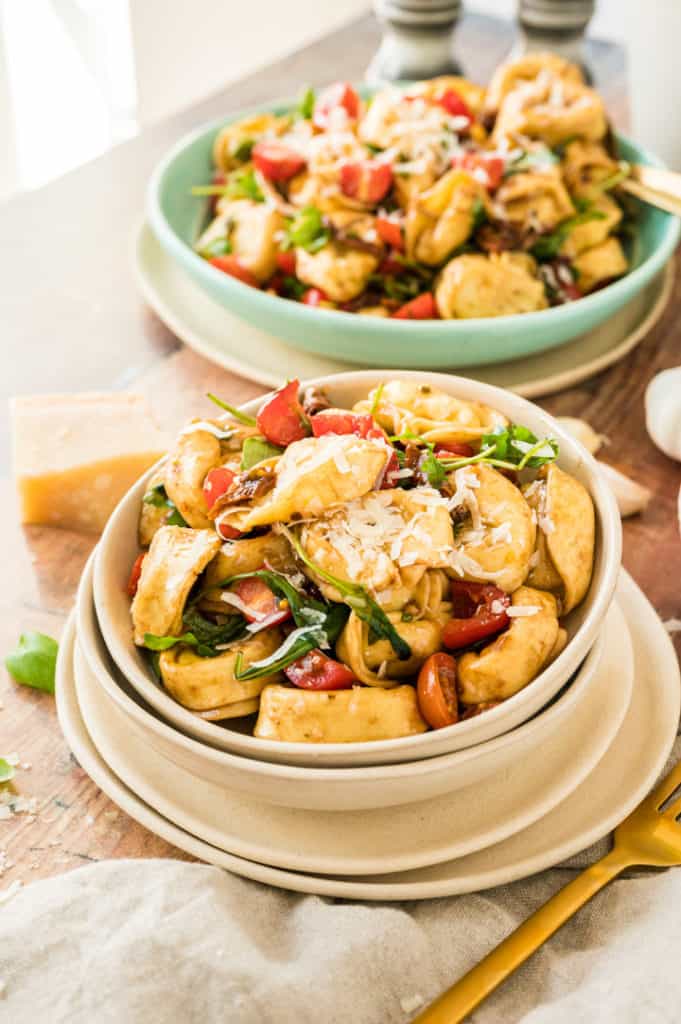 Tortellini-Salat in beiger Schale mit großer Schale im Hintergrund