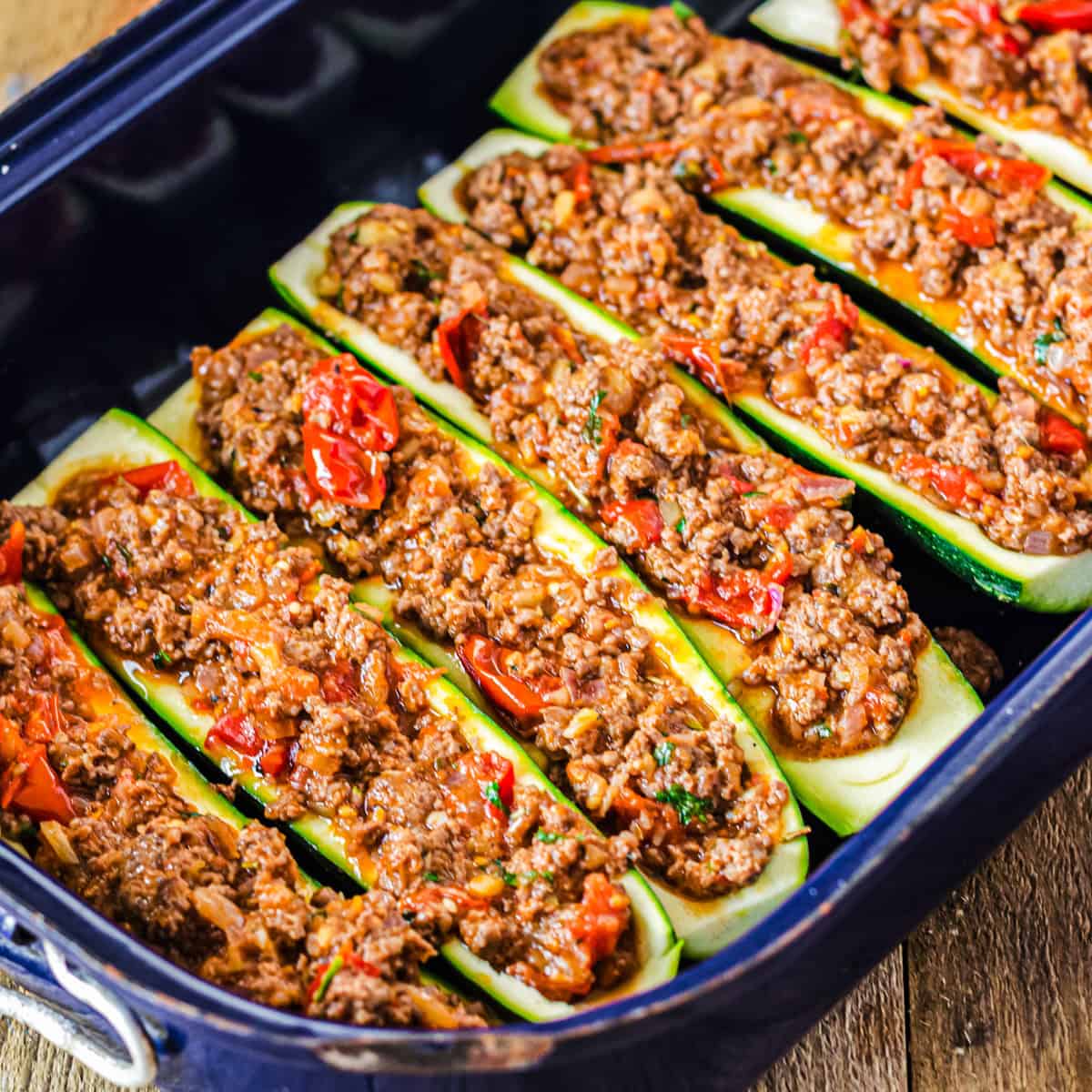 gefüllte Zucchini in blauer Ofenform vor dem Backen