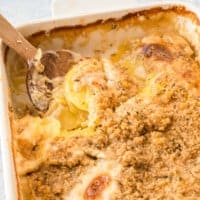Kartoffelgratin in weißer Auflaufform mit Holzlöffel