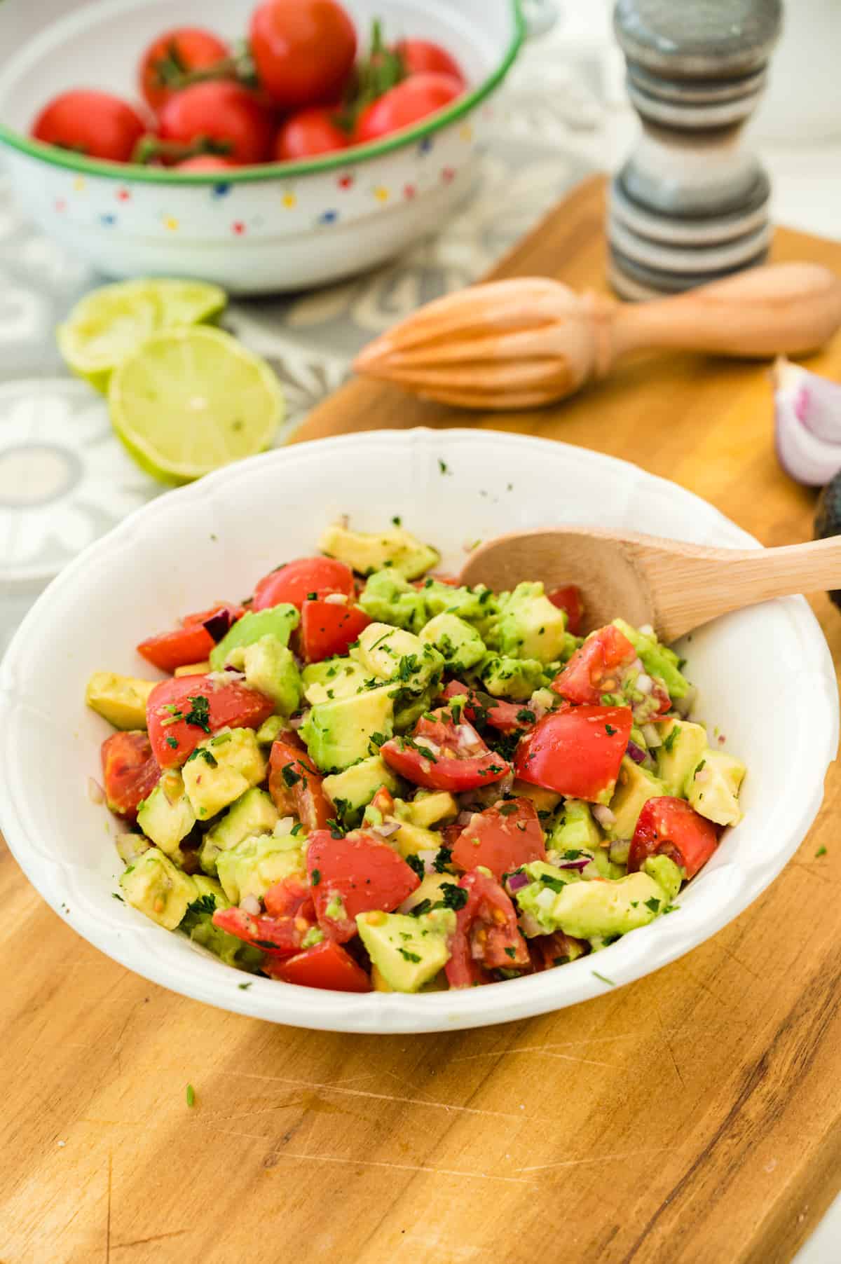 Tomaten-Avocado-Salat in weißer Schüssel auf Holzbrett