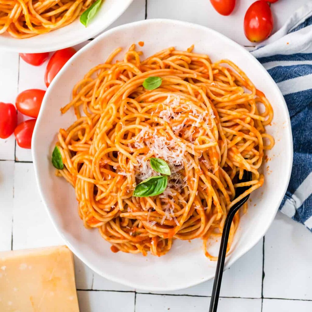 Spaghetti Napoli in weißer Schale mit Basilikum und Parmesan von oben