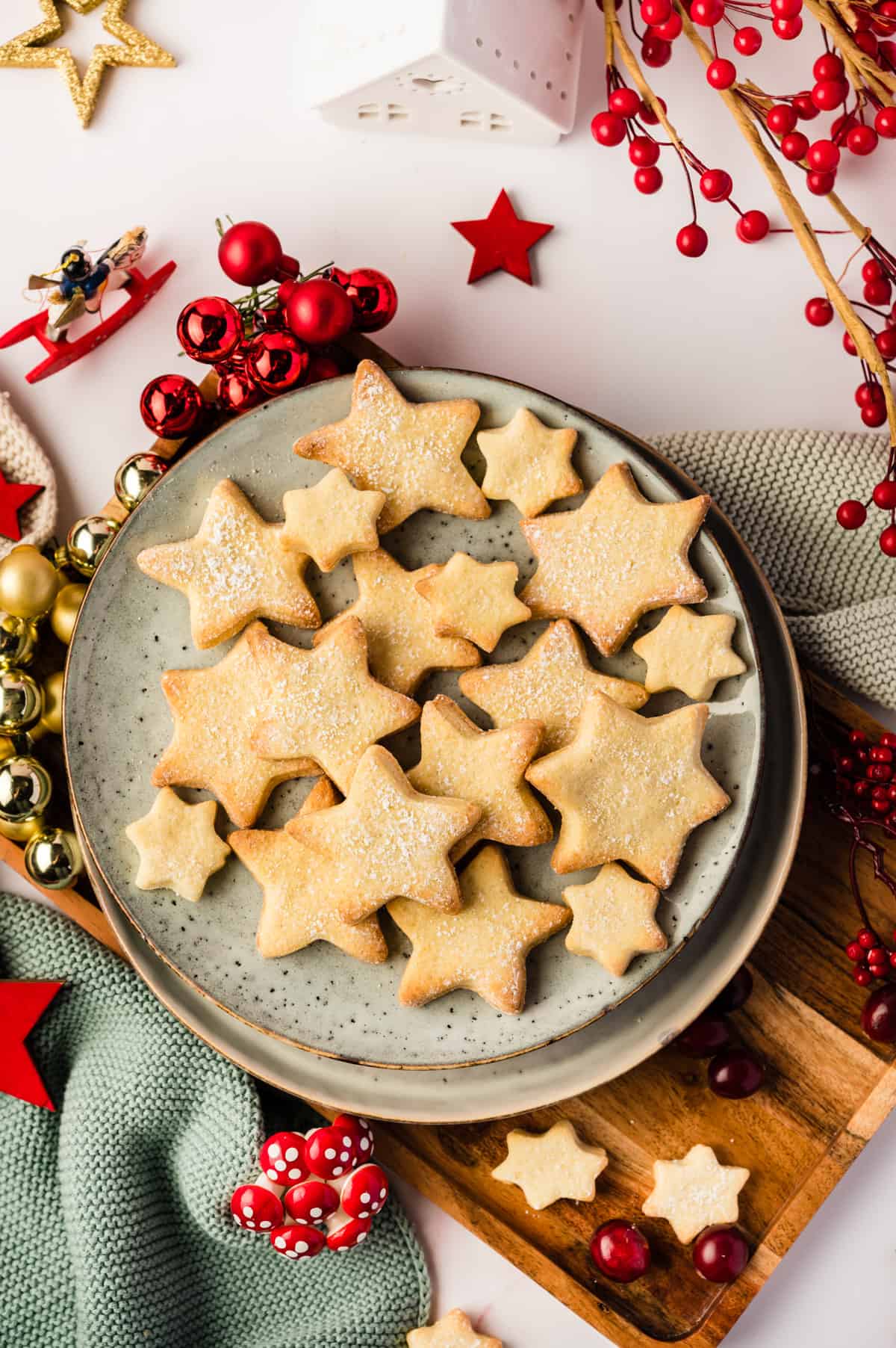 Butterplätzchen in Sternform auf einem hellen Teller mit Weihnachtsdeko drumherum von oben