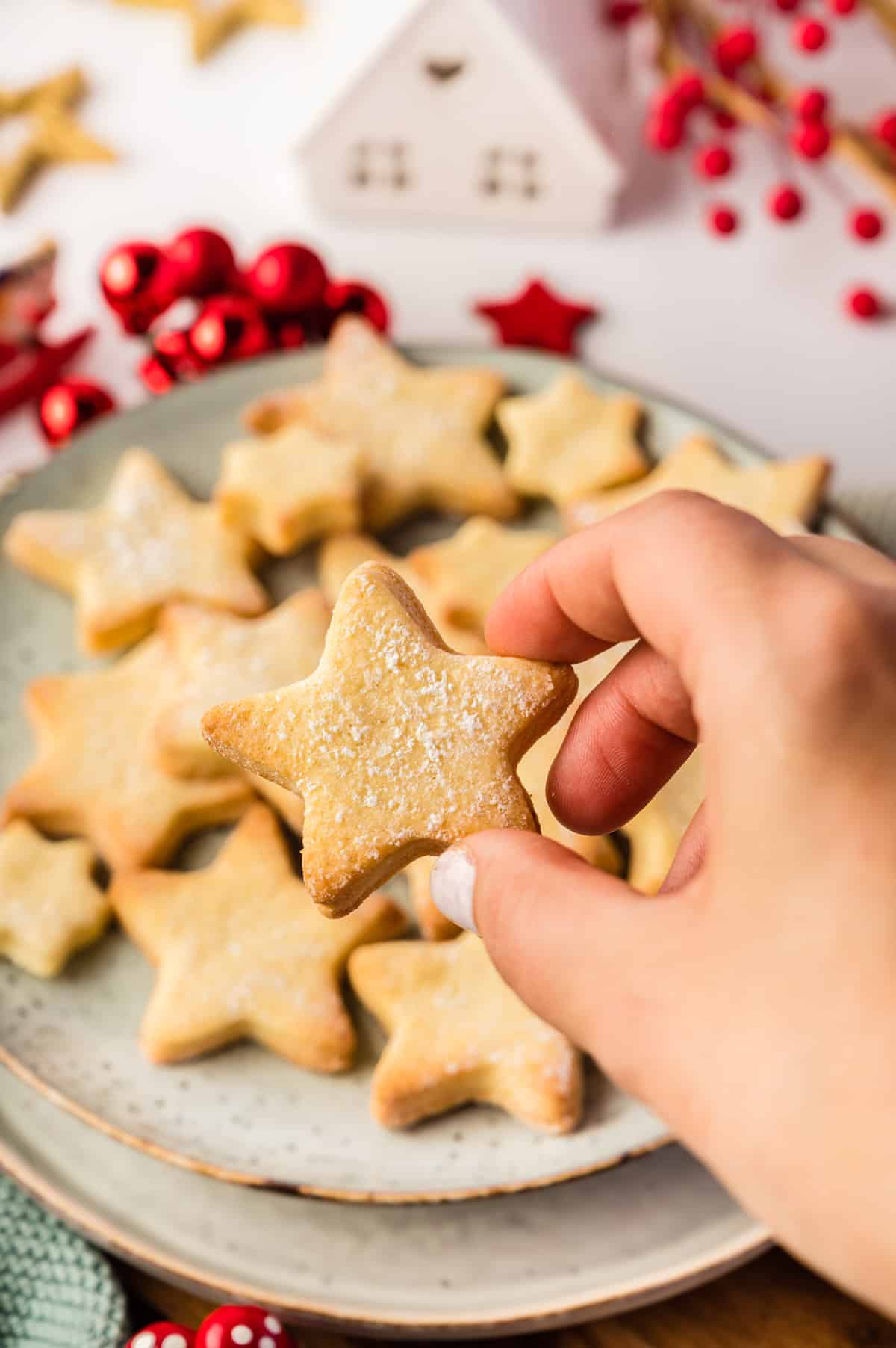 Butterplätzchen in Sternform mit einer Hand hochgehalten