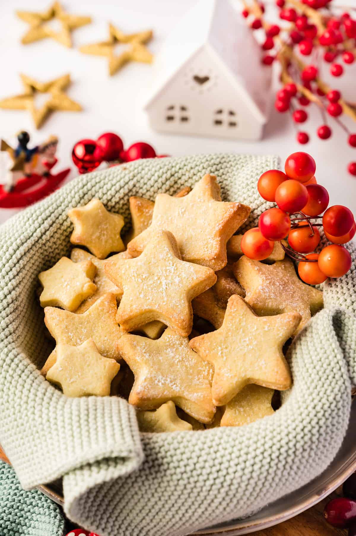 Butterplätzchen in Sternform in einem hellgrünen Korb mit Weihnachtsdeko drumherum