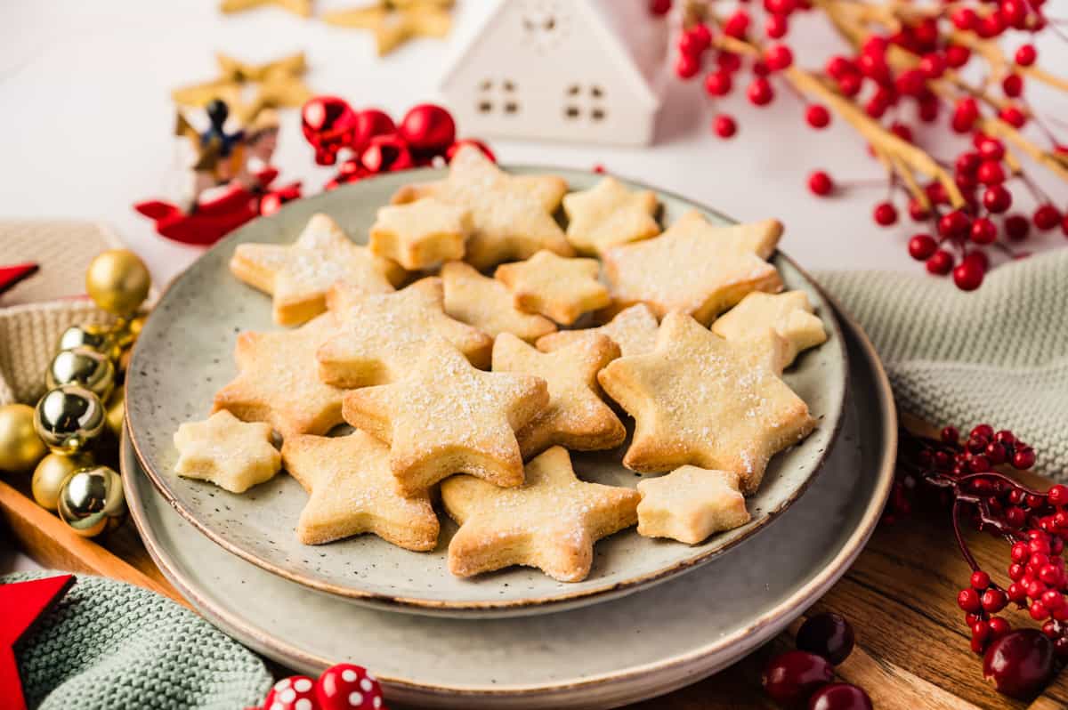 Butterplätzchen in Sternform auf einem hellen Teller mit Weihnachtsdeko drumherum