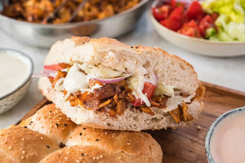 gefülltes Döner auf einem Holzbrett mit Zutaten im Hintergrund