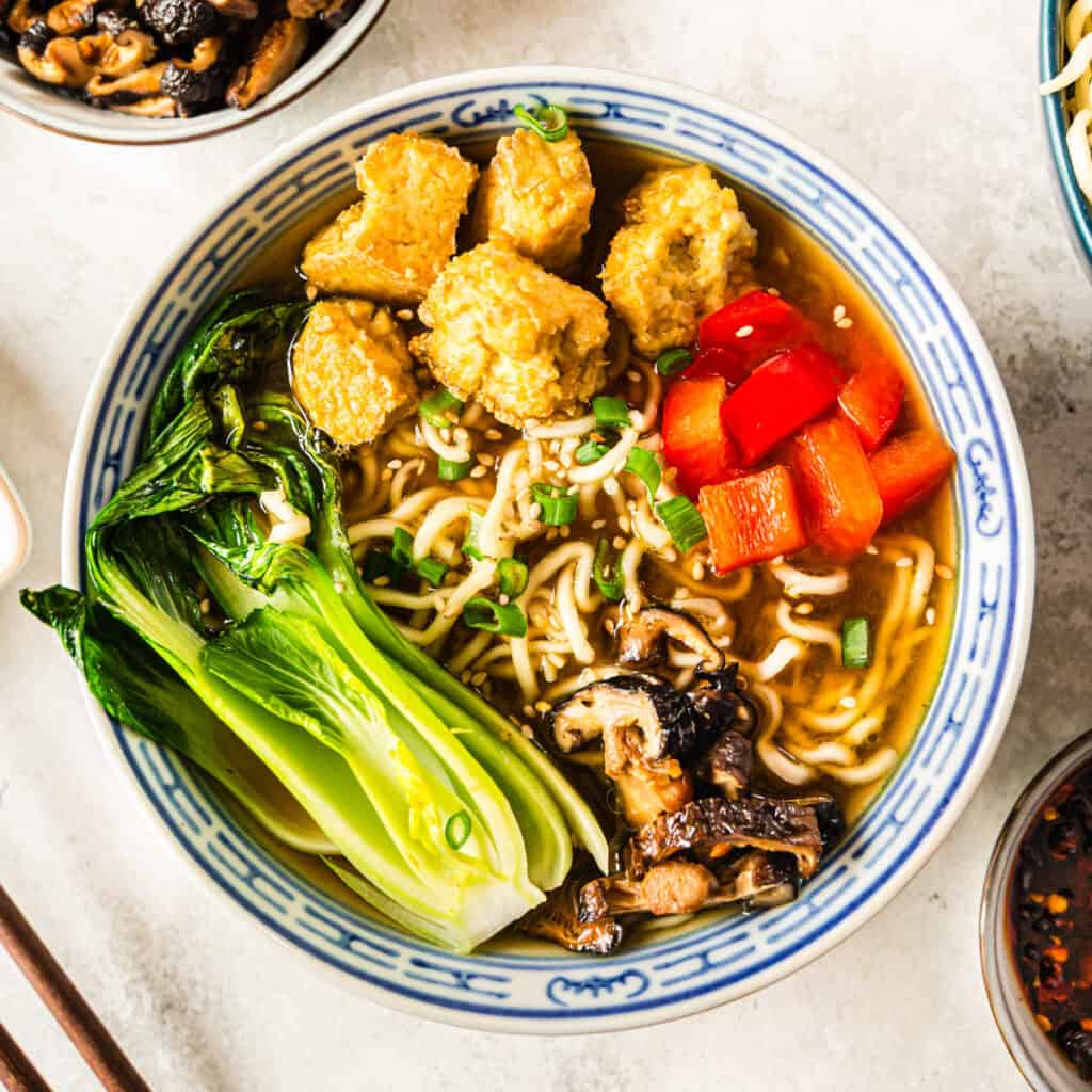 Ramen mit Tofu und Gemüse in blau-weißer Schale mit Holzstäbchen von oben