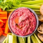Rote Bete Hummus in grauer Schale mit Gemüsesticks drumherum von oben