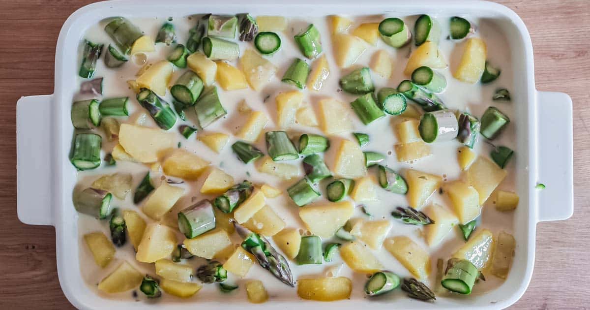 Kartoffeln, grüner Spargel und Sauce in weißer Auflaufform von oben