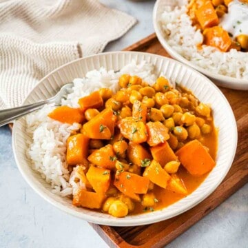 Kürbis Curry mit Reis in heller Schale auf Holzbrett