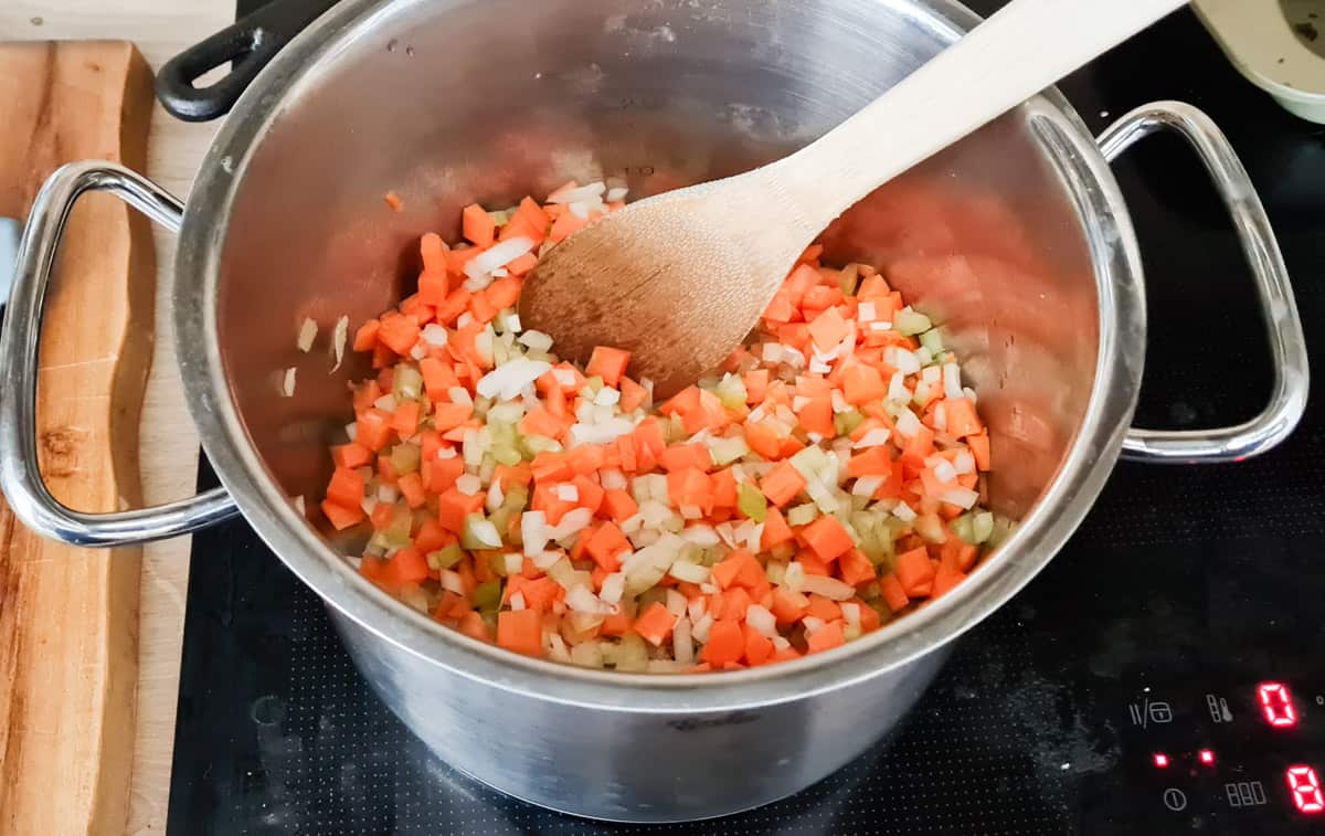 Karotten, Zwiebeln und Sellerie in einem großen Topf, werden angebraten