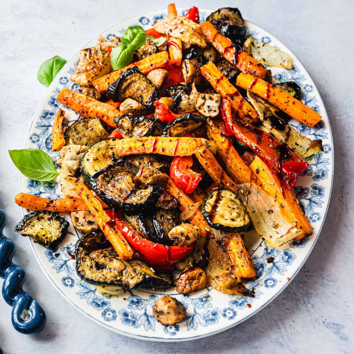 Gemischte Antipasti auf einer weißen Platte mit blauem Blumenmuster am Rand