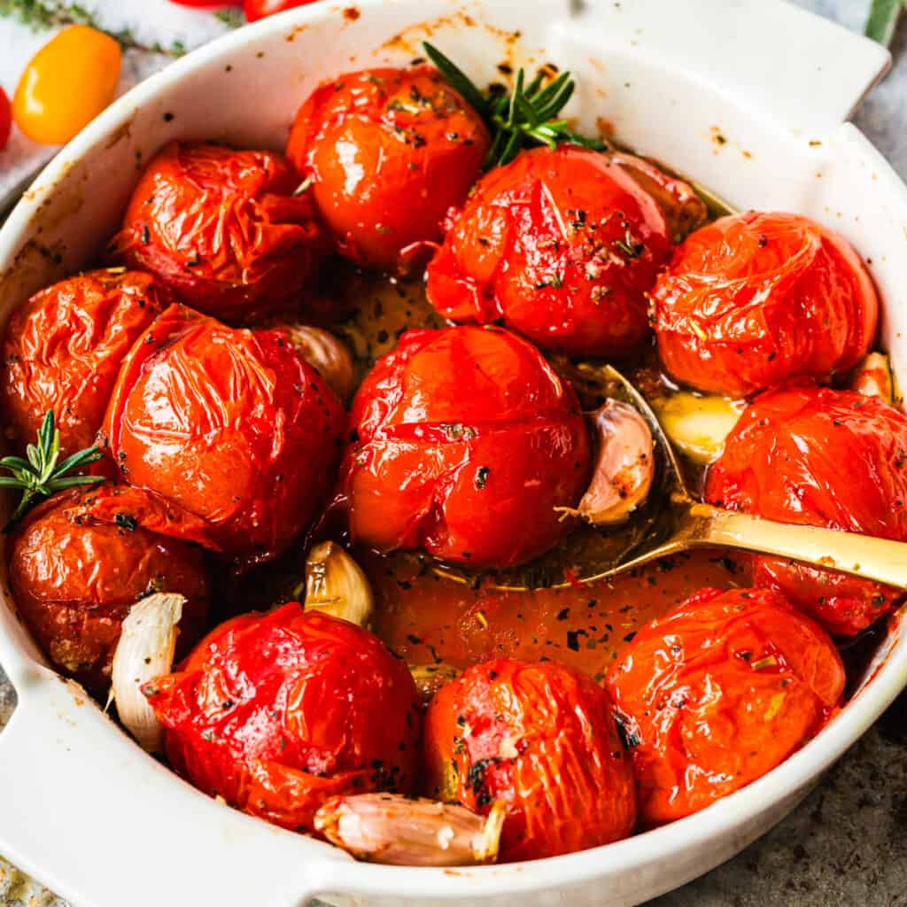 Geschmolzene Tomaten in weißer runder Form mit goldenem Löffel