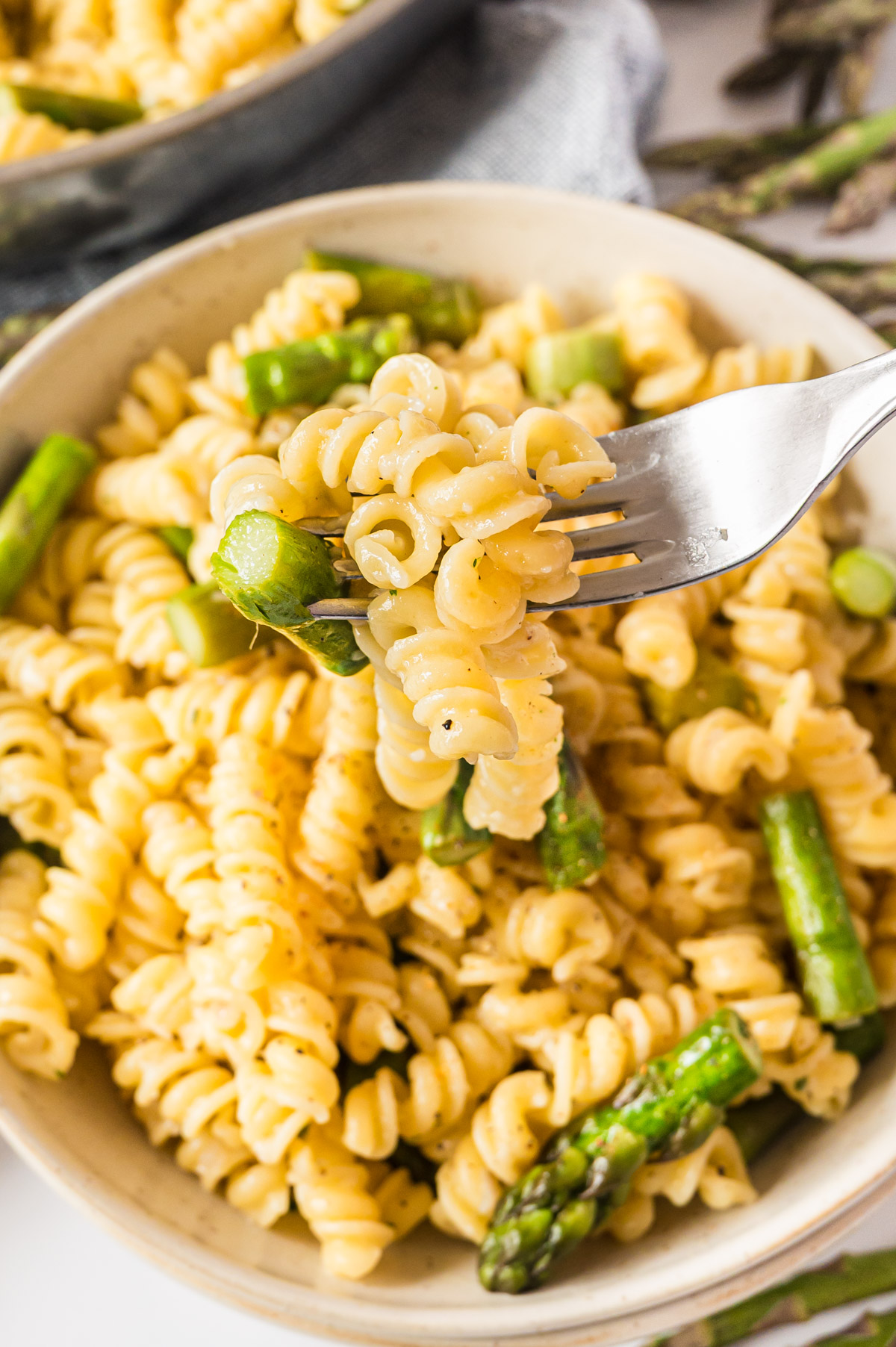 Spargelpasta in heller Schale, Portion auf Gabel aufgespießt