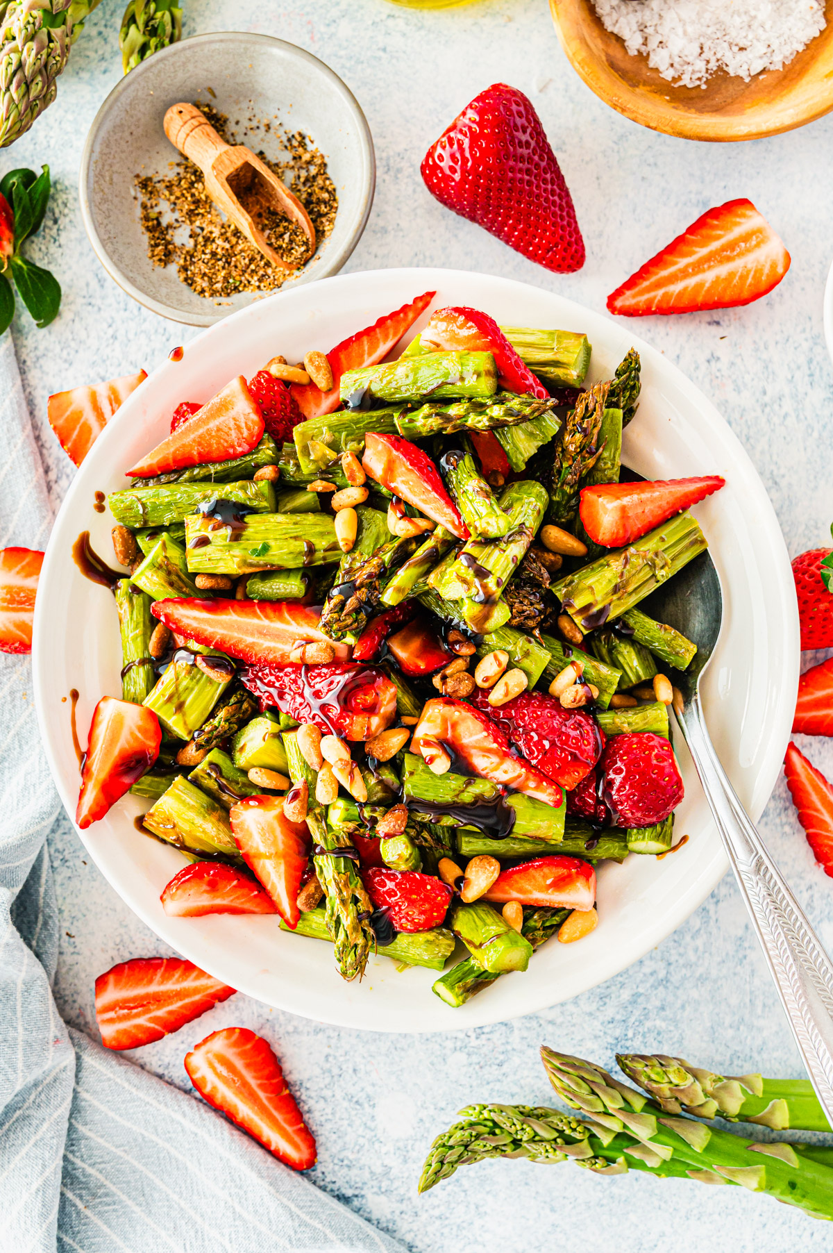 Spargelsalat mit Erdbeeren in weißer Schüssel mit Servierlöffel, von oben