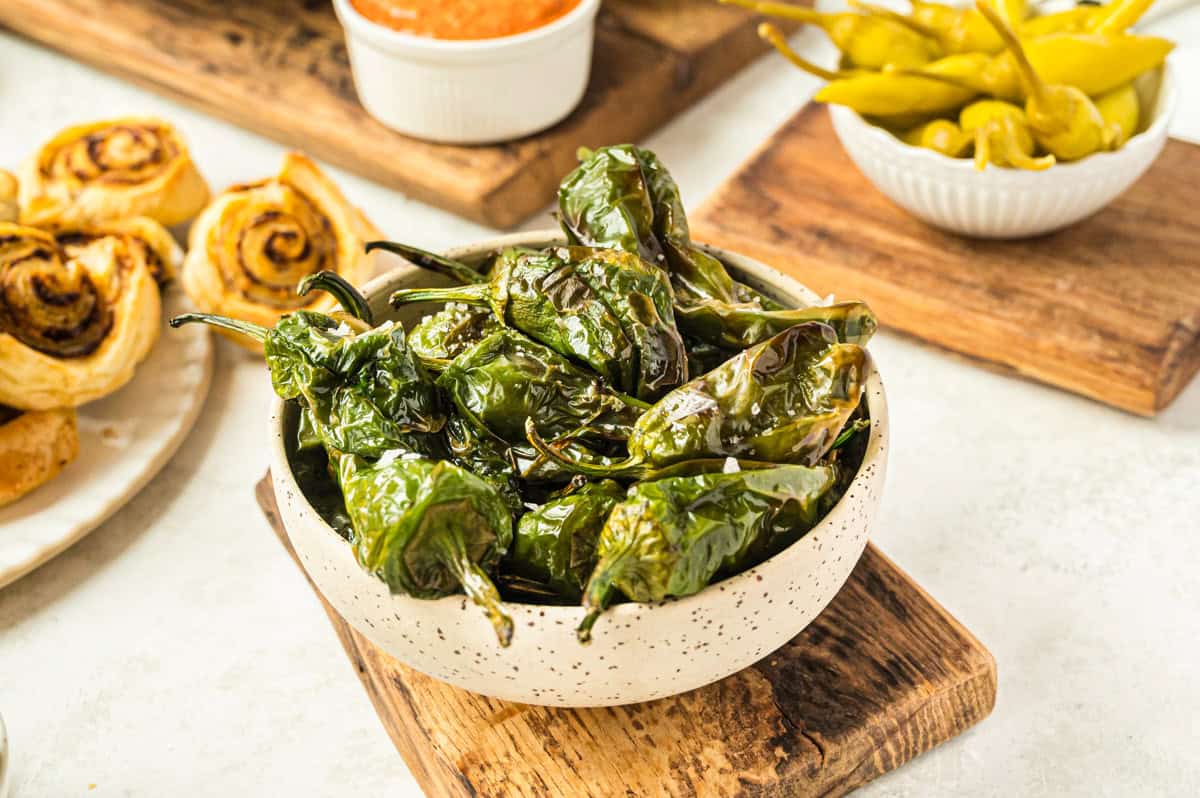 gebackene Pimientos de Padron in heller Schale auf gedecktem Tisch mit Tapas