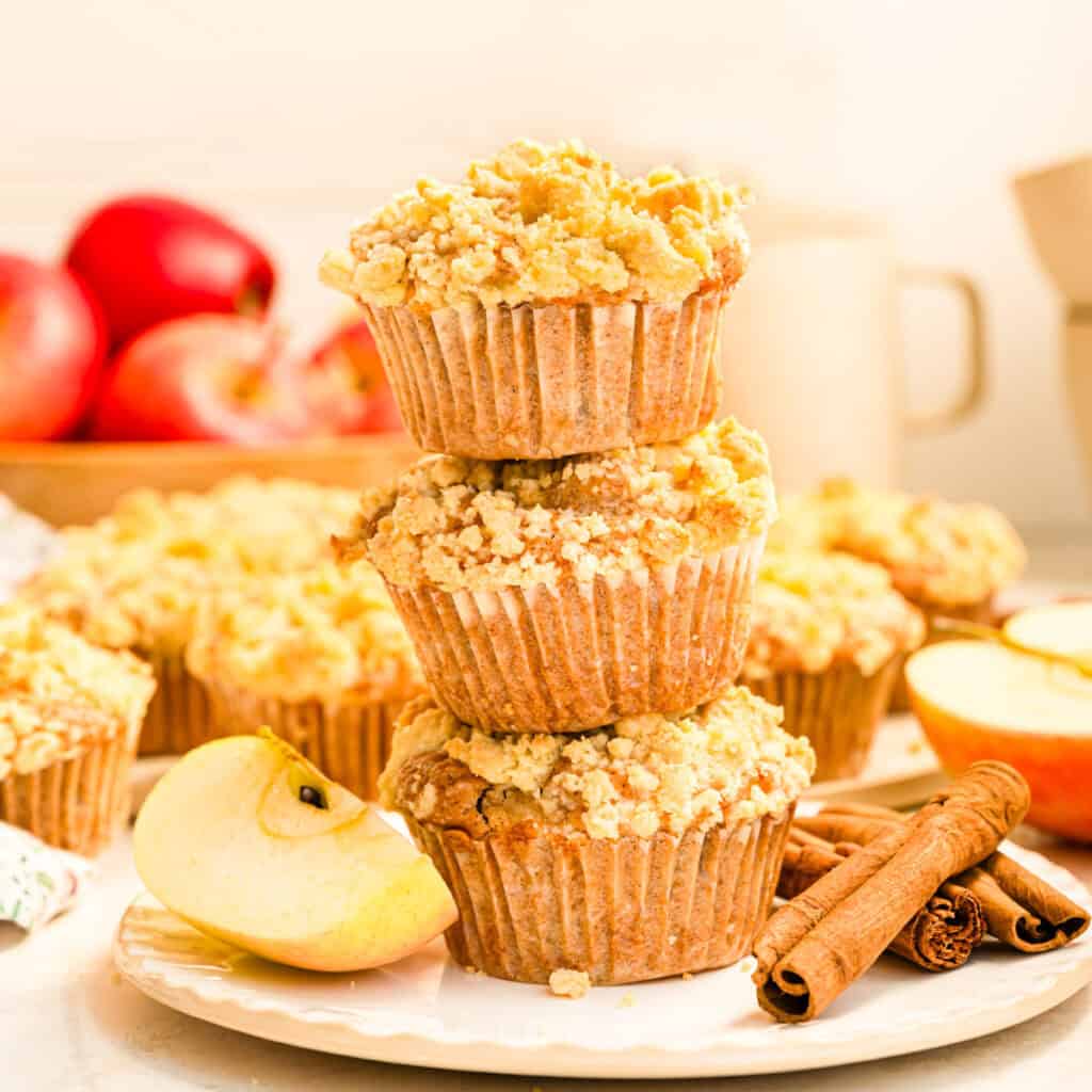 Drei vegane Apfel-Muffins mit Streuseln und Zimt auf weißem Teller gestapelt