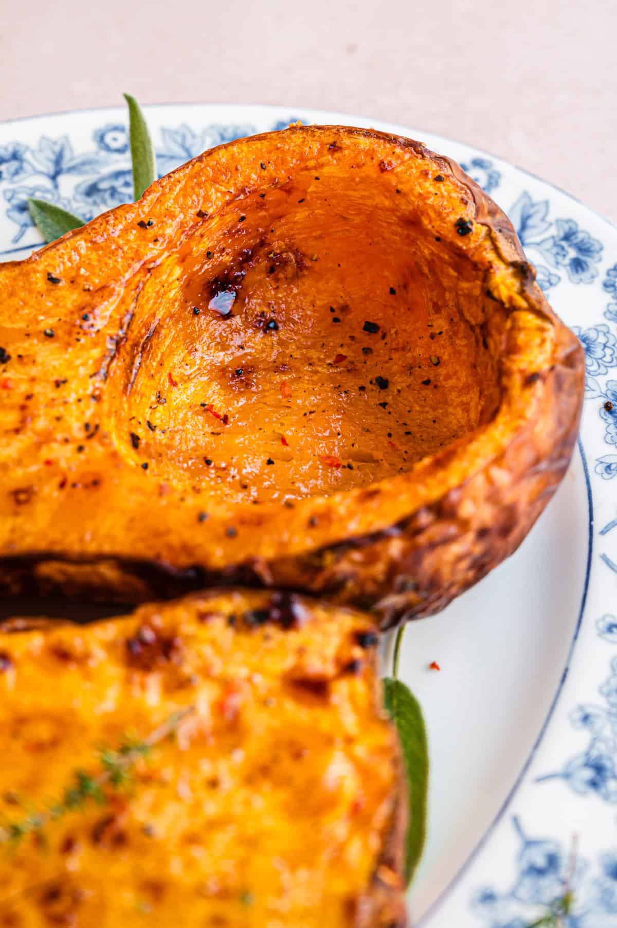 zwei gebackene Butternut Kürbis Hälften auf weißer Servierplatte, in Nahaufnahme