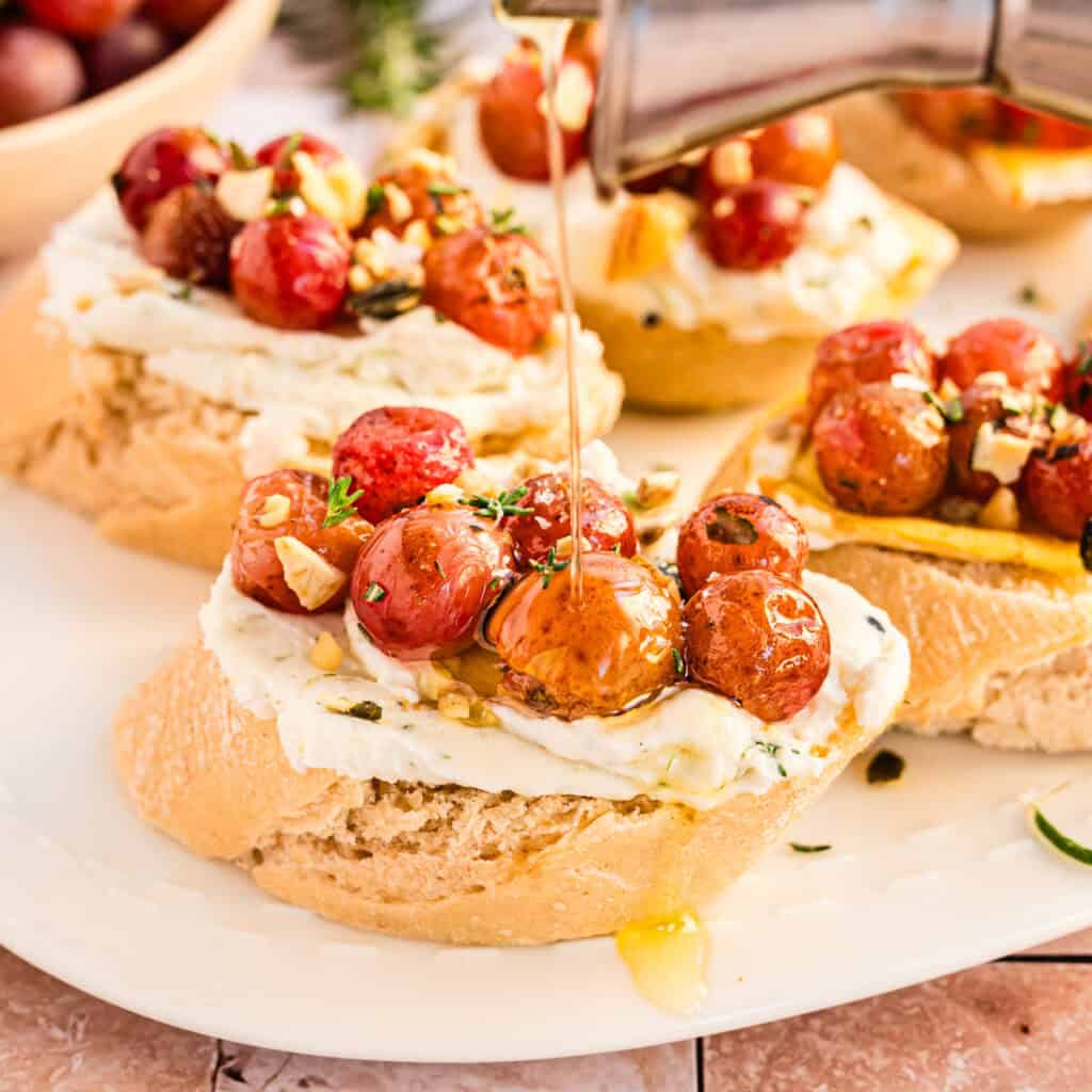 Crostini mit gerösteten Weintrauben, Öl wird drüber geträufelt