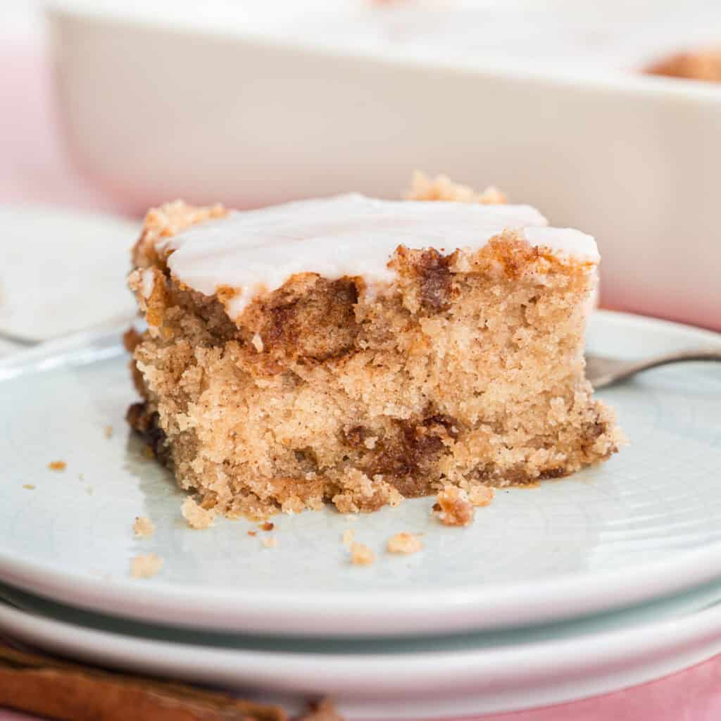 Ein Stück Zimtschneckenkuchen auf zwei hellgrauen Tellern mit Gabel