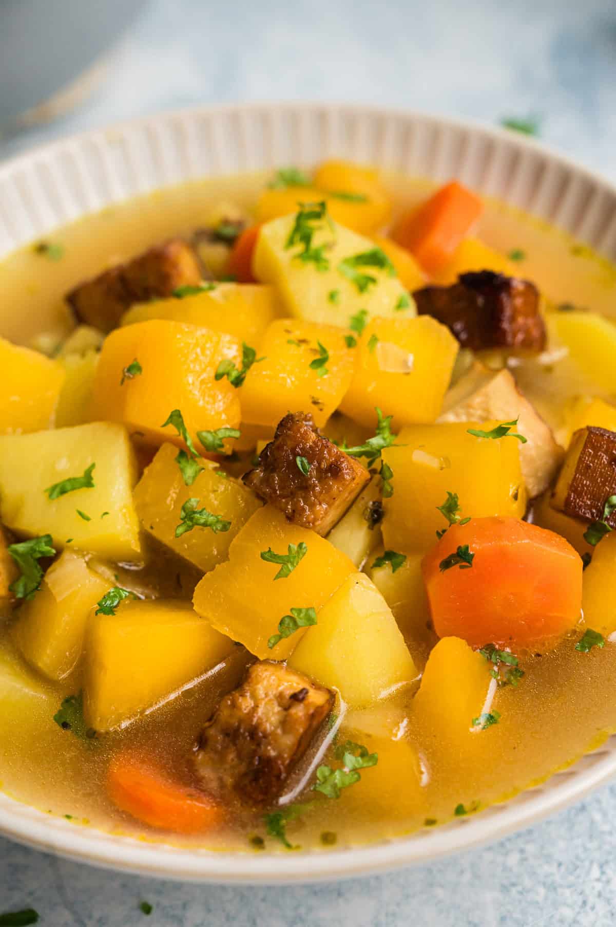 Steckrübeneintopf mit Räuchertofu in heller Schale, in Nahaufnahme