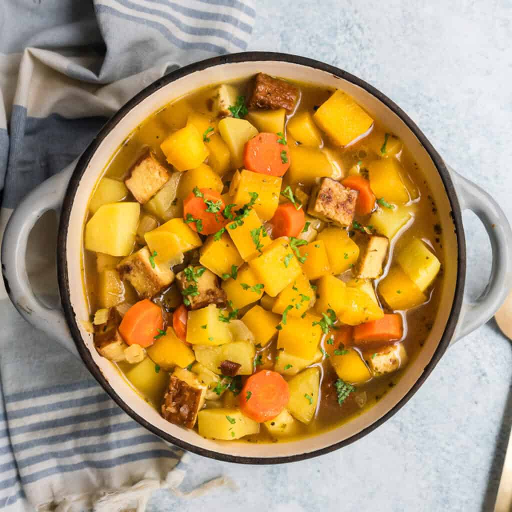 Steckrübeneintopf mit Räuchertofu in grauem Topf, von oben