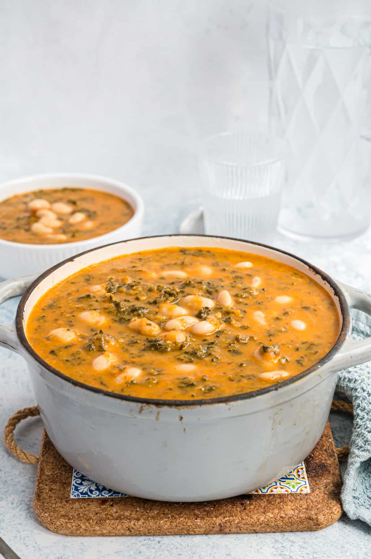 hellgrauer Topf mit Bohnensuppe mit Grünkohl, Schale mit Suppe dahinter