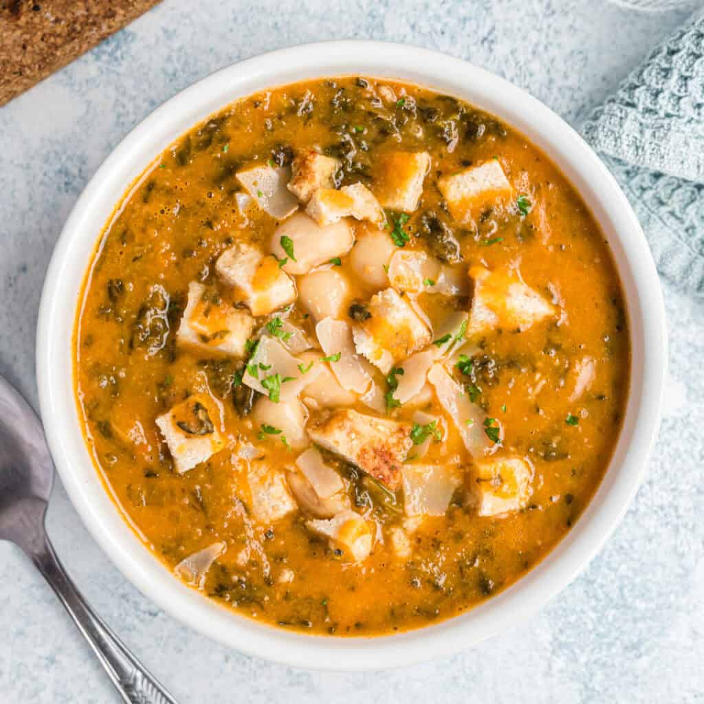 Ribollita mit veganem Parmesan und Petersilie in weißer Schale, Nahaufnahme, von oben