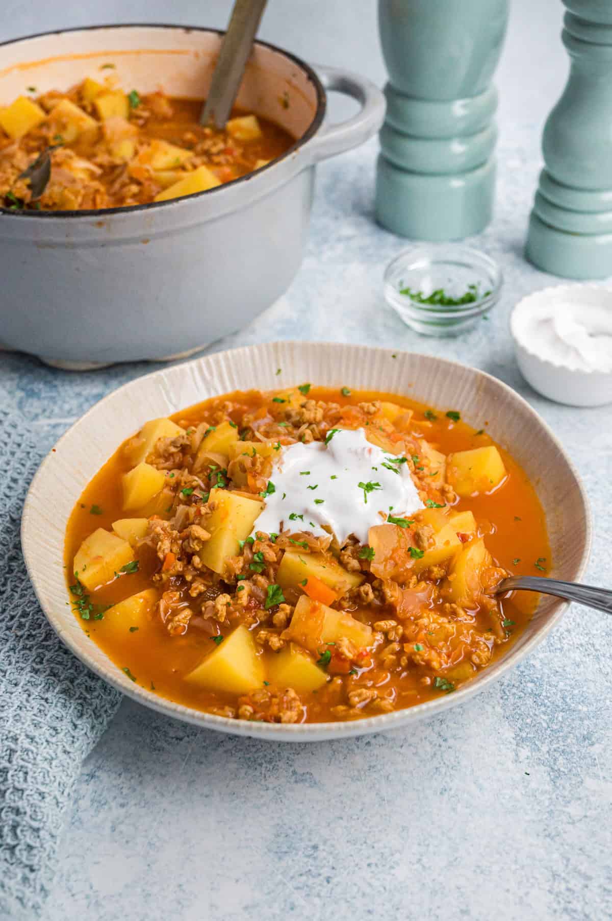 Kartoffelgulasch mit Sauerkraut in heller Schale, mit Topf dahinter