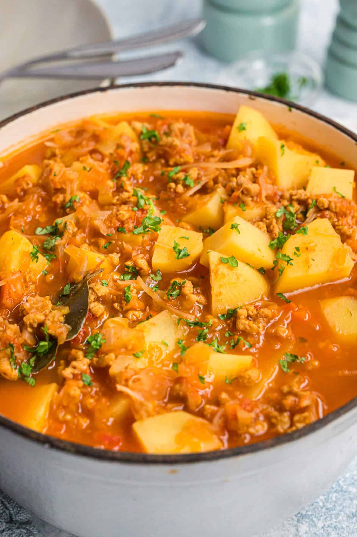 Kartoffelgulasch mit Sauerkraut in hellgrauem Topf, Nahaufnahme