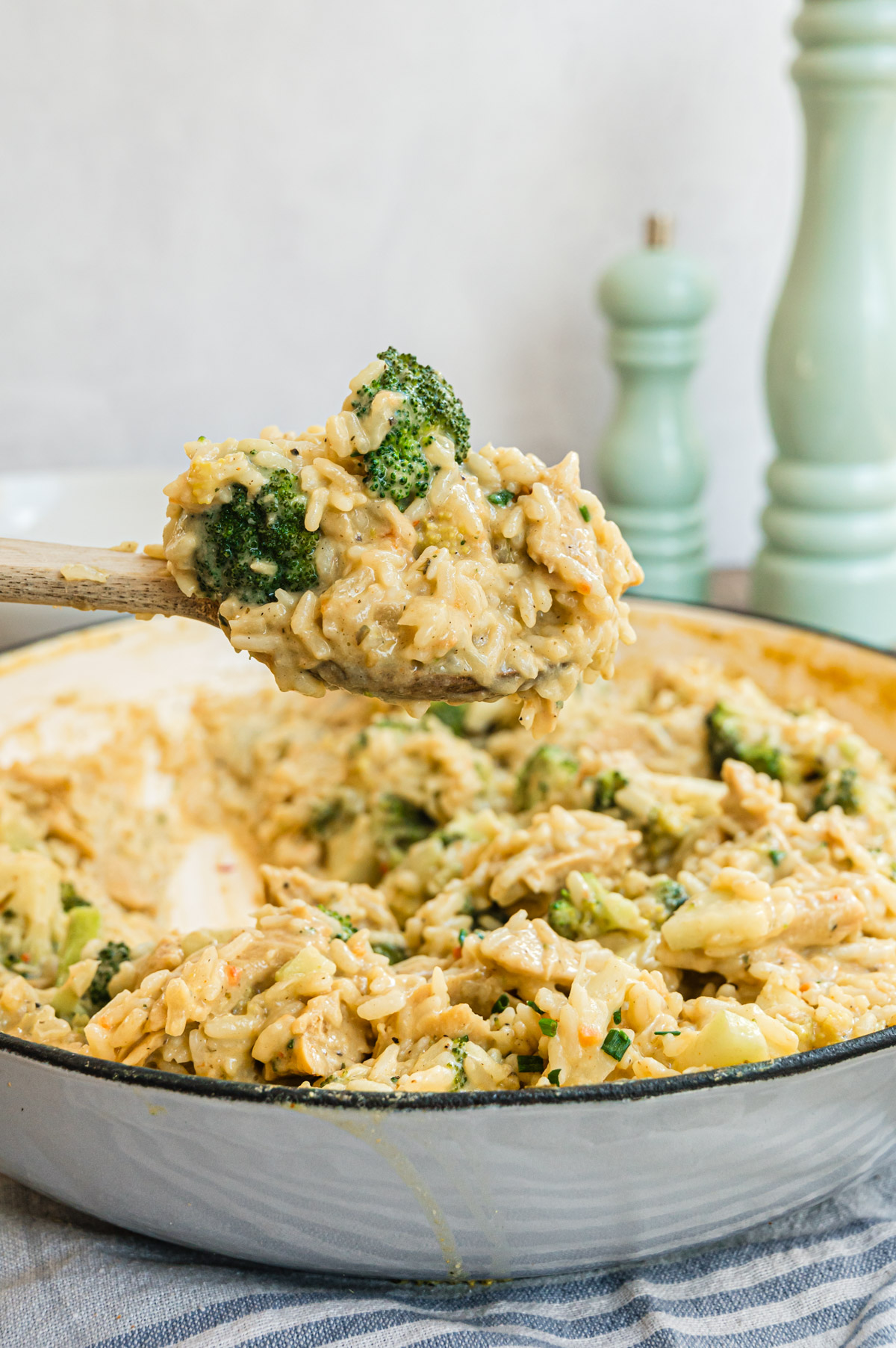 One Pot Reispfanne mit Brokkoli in grauer Pfanne mit Holzlöffel darüber