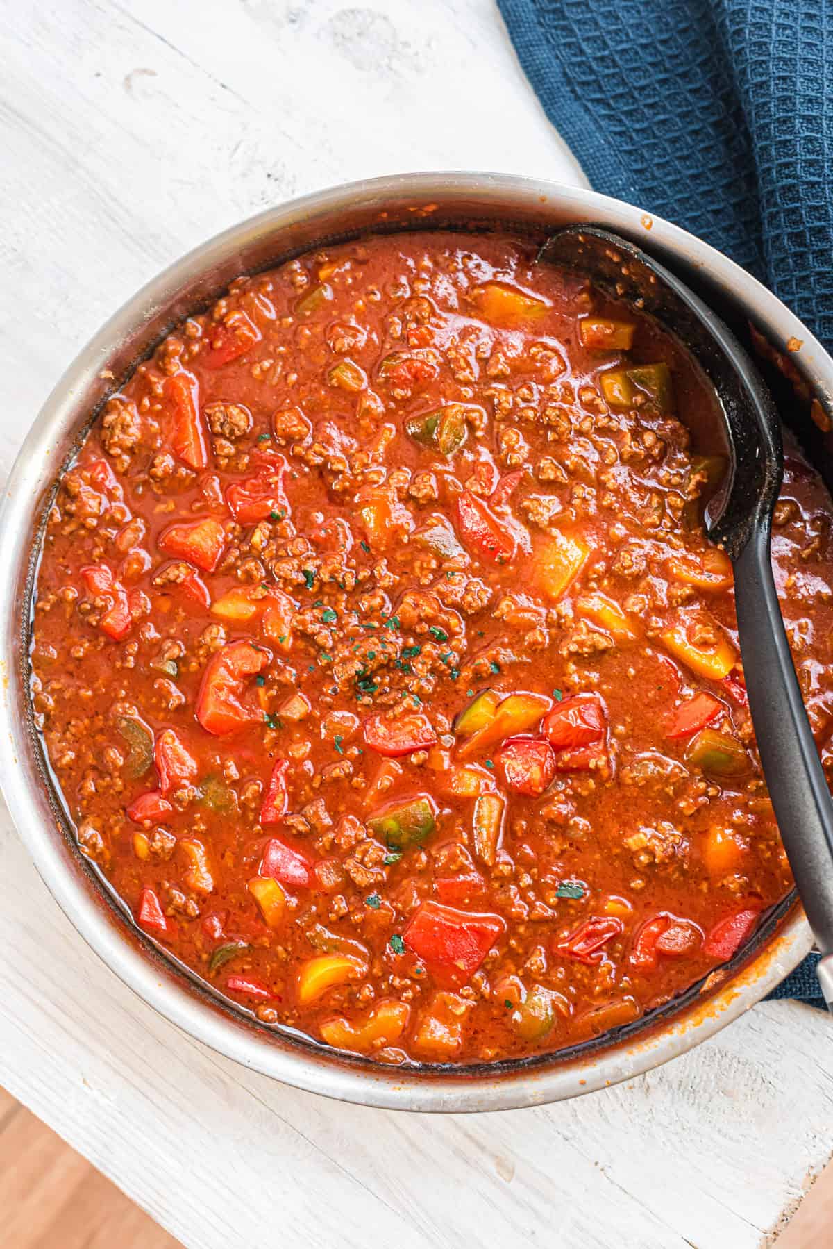 Paprika-Hackpfanne in Edelstahlpfanne mit schwarzer Kelle, von oben