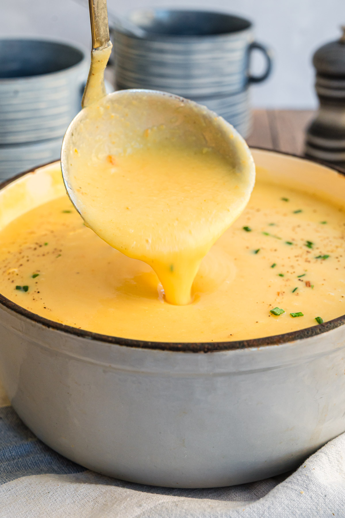 Kartoffelsuppe wird von Suppenkelle in Topf gegossen