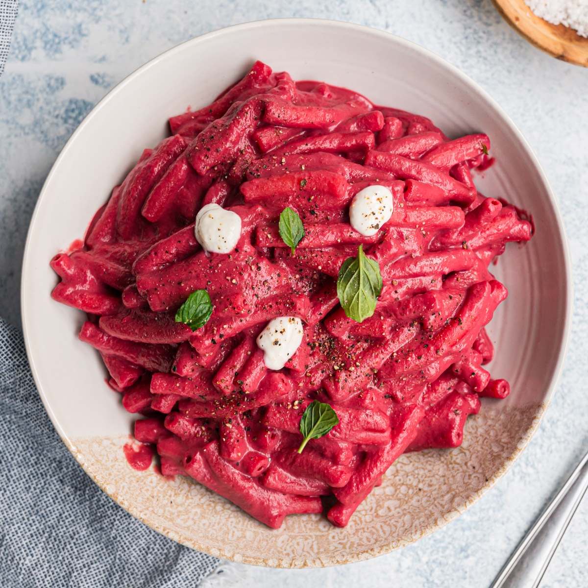 Vegane Pink Pasta in heller Schale mit Minze und Merrettich dekoriert, von oben